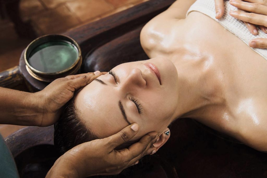 A woman getting her face washed with oil.