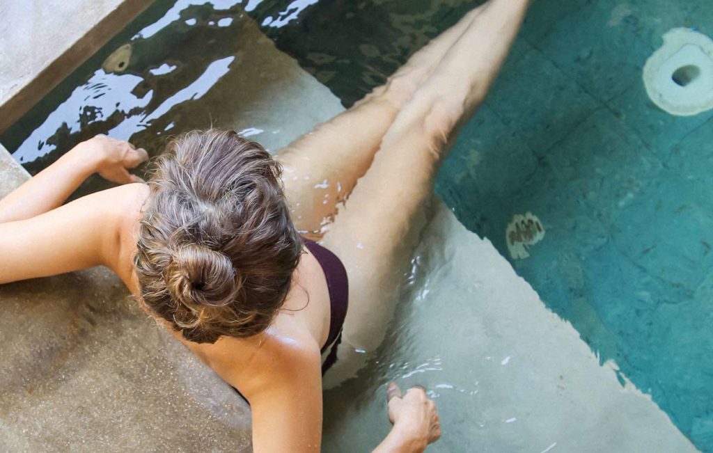 A woman in the water at the edge of a pool.