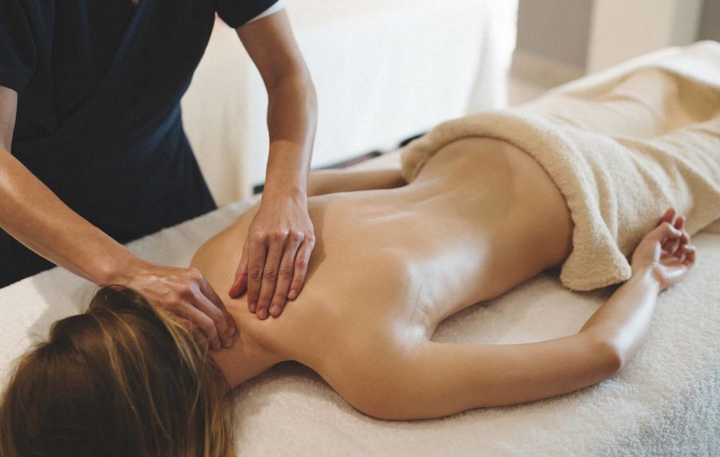 A woman getting her back touched by a masseuse.