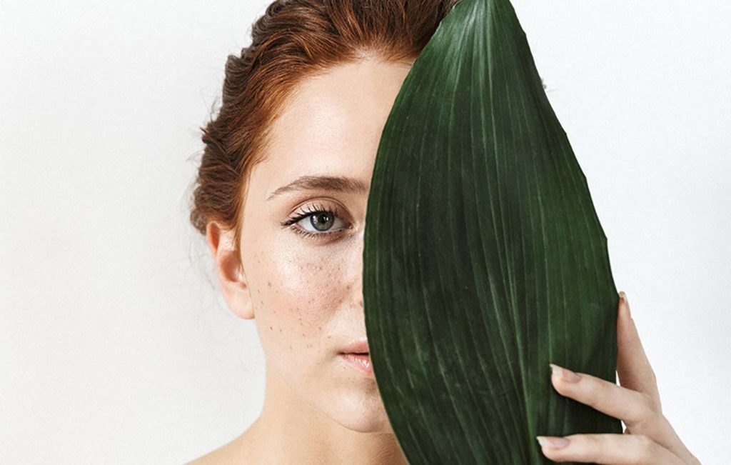 A woman with red hair holding up a leaf.